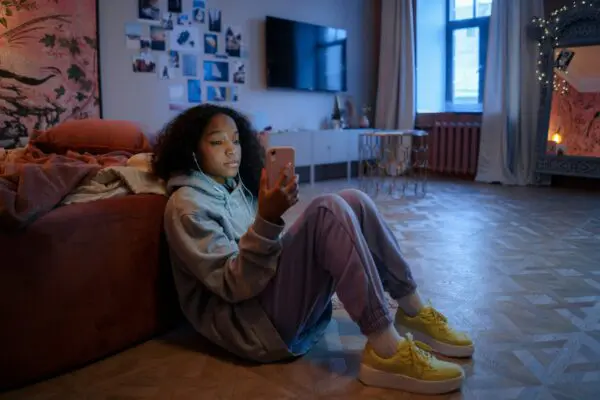 A young teen uses their phone at night in their room.